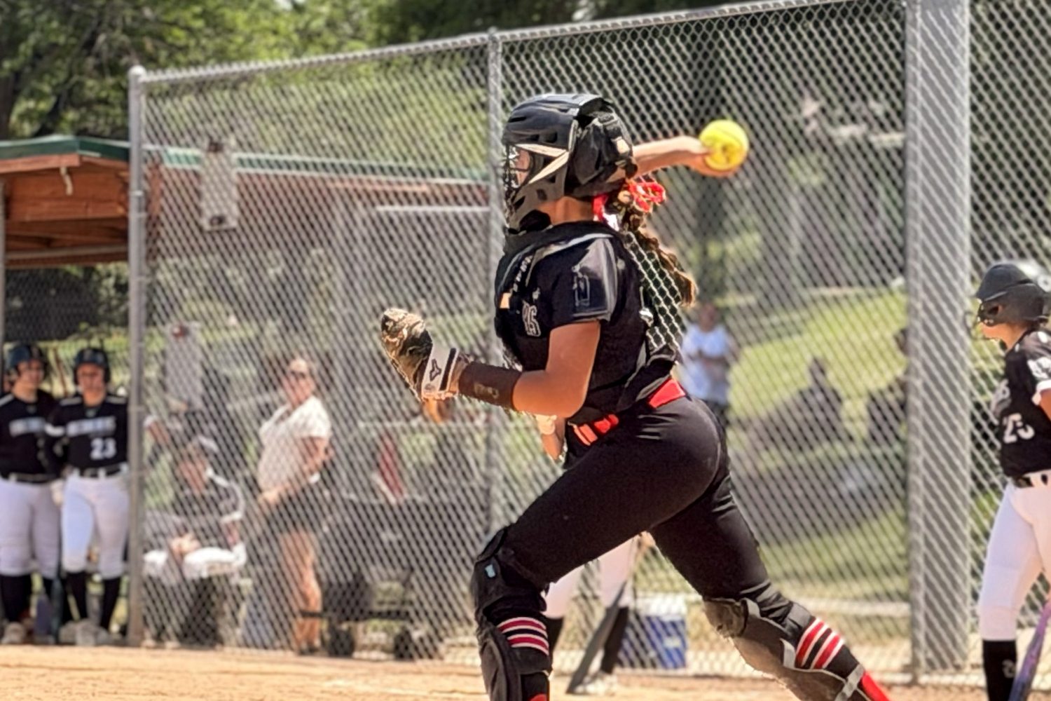 Mia Mead throwing to second base from behind the plate, ball just out of her hand